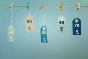 Labels hang on a rope attached with clothespins. The values of the discount are written on them, fifty, thirty, sixty percent. Photo on a blue background.