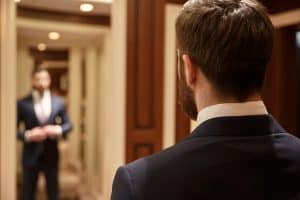 Man looking in mirror wearing suit